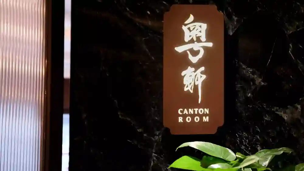 香港六國酒店內中菜廳**粵軒(Canton Room)**的招牌特寫,招牌發光,背景是黑色大理石牆,展現高級粵菜餐飲格調