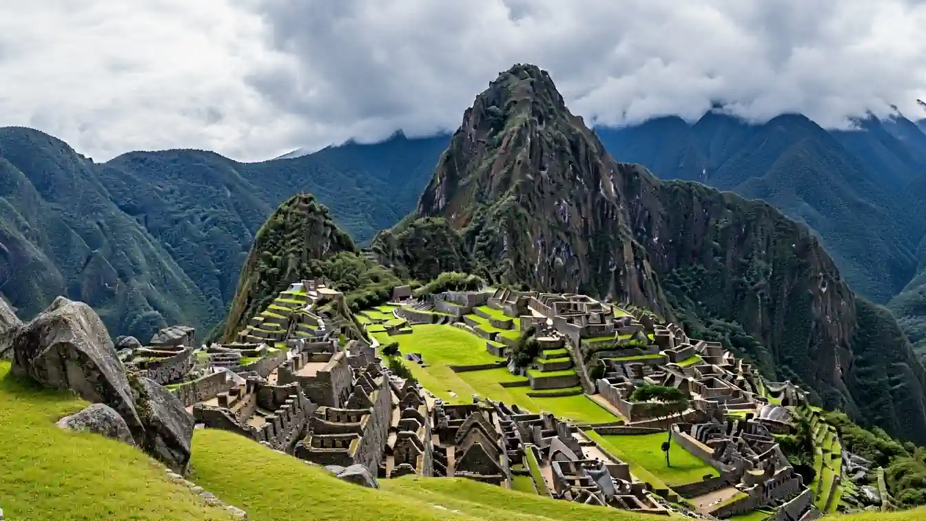秘魯雙城精華七日小包團必訪景點：馬丘比丘印加古城遺址全景，背景為宏偉的瓦納比丘山與雲霧繚繞的安地斯山脈。