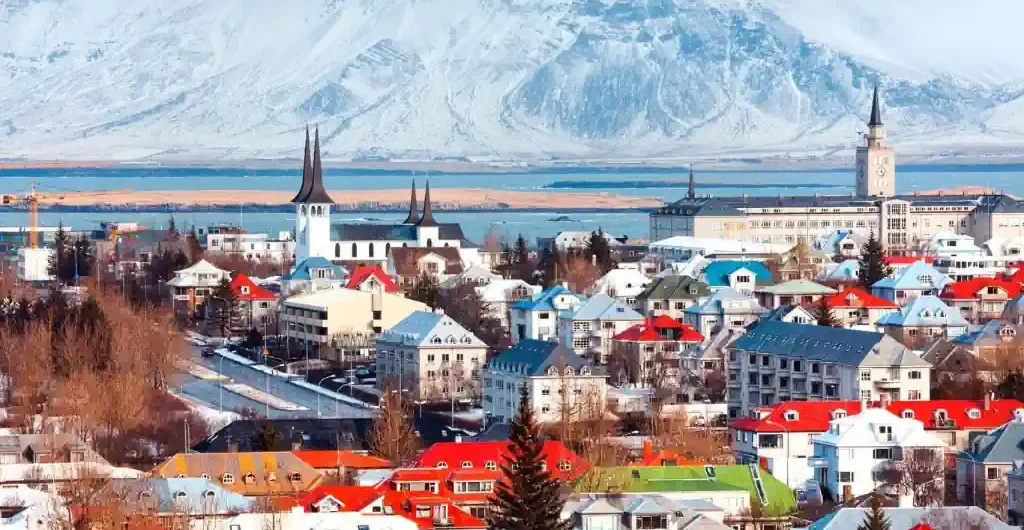 冰島首都雷克雅維克全景，色彩繽紛的房屋屋頂與遠處宏偉的雪山，是冰島6天5夜私人小包團的必經之地。