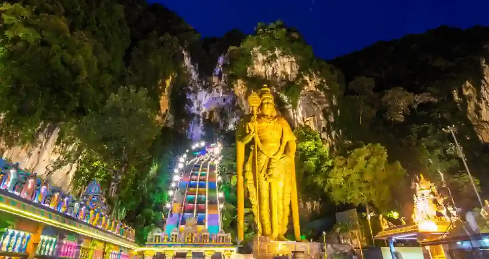 馬來西亞黑風洞夜景,壯觀的金身室建陀神像與亮起燈光的彩虹階梯,展現濃厚的印度教文化氛圍。