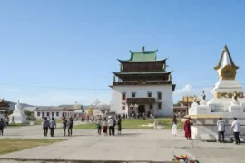 蒙古烏蘭巴托甘丹寺，白色宏偉的章冉澤大佛殿建築，前方有白色的佛塔與穿梭於廣場的信眾。