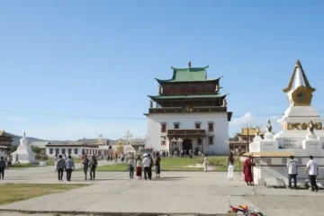 蒙古烏蘭巴托甘丹寺，白色宏偉的章冉澤大佛殿建築，前方有白色的佛塔與穿梭於廣場的信眾。