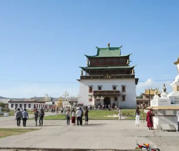 蒙古烏蘭巴托甘丹寺，白色宏偉的章冉澤大佛殿建築，前方有白色的佛塔與穿梭於廣場的信眾。